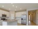 Modern kitchen with white cabinetry, stainless appliances, island, and view to the entry way at 5006 Abigail Dr, Lake Wales, FL 33859