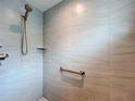 Tiled shower featuring a shower head, corner shelf, and grab bar for added safety at 6633 Holovak Ter, The Villages, FL 34762
