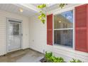 A cozy entryway featuring a storm door, red shutters, and well-maintained vinyl siding at 8932 Se 168Th Sedgwick Pl, The Villages, FL 32162