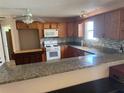 Well-lit kitchen features wooden cabinets, backsplash, granite countertops, and updated appliances at 8932 Se 168Th Sedgwick Pl, The Villages, FL 32162