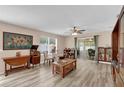 Inviting living room with wood-look flooring, ceiling fan, and sliding glass doors to the lanai at 8932 Se 168Th Sedgwick Pl, The Villages, FL 32162