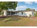 A green backyard featuring a screened lanai, lawn, and garden bed at 1 Aberdeen Cir, Leesburg, FL 34788