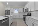 Bright kitchen with stainless steel appliances, island with sink, white cabinets, and backsplash at 12624 Ne 49Th Dr, Oxford, FL 34484