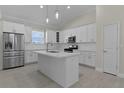 Modern kitchen with stainless steel appliances, island with sink, white cabinets, and pendant lights at 12624 Ne 49Th Dr, Oxford, FL 34484