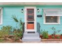 Close-up of front door with brick accents and updated sconces, surrounded by lush landscaping at 1301 North Ave, Tavares, FL 32778