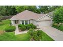 Charming single-story home with well-maintained landscaping, complemented by a two-car garage and inviting walkway at 13050 Se 89Th Cir, Summerfield, FL 34491