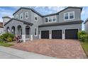 Gray two-story home featuring a brick driveway leading to a three-car garage at 14513 Winter Stay Dr, Winter Garden, FL 34787