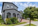 Gray two-story home showcasing arched entryway, brick driveway, and lush landscaping at 14513 Winter Stay Dr, Winter Garden, FL 34787