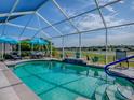 Sparkling pool area features screened enclosure, seating areas, and serene backyard views at 17563 Se 122Nd Ter, Summerfield, FL 34491