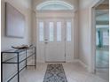 Inviting foyer with tile flooring, decorative glass door, and modern console table at 2044 Larkwood Ct, The Villages, FL 32162