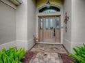 Elegant front door with decorative glass panels and transom window, complemented by lush greenery at 2044 Larkwood Ct, The Villages, FL 32162