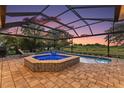 Inviting screened-in pool and spa with brick patio, lights and lovely sunset view at 2125 Horizon Run, The Villages, FL 32162