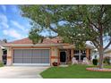 Charming single-story home featuring a screened garage, welcoming front porch with rocking chairs, and a well-manicured lawn at 21646 Stirling Pass, Leesburg, FL 34748