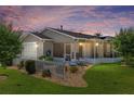 Backyard view of a cozy home with screened lanai, set in a landscaped yard at sunset at 2348 Riley Rd, The Villages, FL 32162