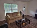 Bright living room featuring neutral-toned sofa, modern flooring, and natural light from the large window at 254 Locust Pass Dr, Ocala, FL 34472