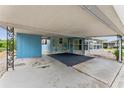 Covered carport area showing the home's light blue exterior, brick accents, and a black paved entrance at 2706 Vindale Rd, Tavares, FL 32778