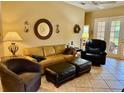 Inviting living room featuring a tan leather couch, chair, ottomans, and a ceiling fan at 3083 Pinnacle Ct, Clermont, FL 34711