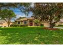 Landscaped single-story home with manicured lawn, palm trees, and charming stone accents at 3141 Brighton Rd, Eustis, FL 32726