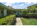 Welcoming entrance with a vibrant blue door, decorative wreath, and lush, green landscaping at 33637 E Lake Joanna Dr, Eustis, FL 32736