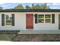 Welcoming front entrance with red door, black shutters and a tidy yard area for enhanced curb appeal at 525 Oak Dr, Tavares, FL 32778
