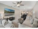 Cozy living room featuring a large sectional sofa, TV, ceiling fan, and neutral tones at 6816 Perch Hammock Loop, Groveland, FL 34736