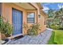 Home's front door with a gray paver walkway, plants, and a beautiful blue door at 684 Grand Canal Dr, Kissimmee, FL 34759