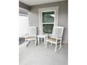 Relaxing front porch furnished with two white rocking chairs and a small table, perfect for enjoying the outdoors at 7394 Lussier Ct, The Villages, FL 34762