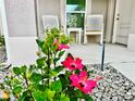 Close-up of the cozy front porch, with white rocking chairs and vibrant hibiscus flowers, creating a welcoming entrance at 7394 Lussier Ct, The Villages, FL 34762