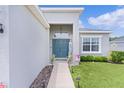 Close-up of front entrance with a teal door, sidelight window, and lush landscaping at 8978 Se 42Nd Ct, Ocala, FL 34480