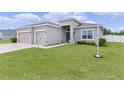 Inviting home exterior with a well-manicured lawn, tidy landscaping, and a spacious three-car garage at 8978 Se 42Nd Ct, Ocala, FL 34480
