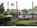 Resort-style pool area surrounded by palm trees, a pool house, black fencing, and manicured landscaping at 10115 Regent Park Dr # 2503, Orlando, FL 32825