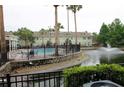 Scenic community pool with a lake view, palm trees, and a black metal fence, perfect for relaxation at 10115 Regent Park Dr # 2503, Orlando, FL 32825