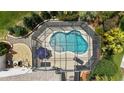Overhead view of a private screened-in pool featuring a kidney shape, clear water, and umbrella-shaded furniture at 1053 Alcove Loop, The Villages, FL 32162