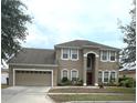 Well maintained two-story house with green grass, brown mulch, and a two car garage at 108 Whispering Pines Way, Davenport, FL 33837