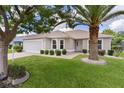 Inviting single-story home featuring a well-manicured lawn, a two-car garage, and lovely landscaping at 1813 Caryle Ln, The Villages, FL 32162