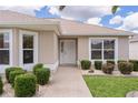 Inviting exterior showcasing a well-kept lawn, front door, manicured bushes, and natural light at 1813 Caryle Ln, The Villages, FL 32162