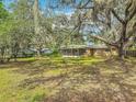 A spacious backyard featuring mature trees, a lawn, and a screened-in porch, offering privacy at 2216 River Ridge Rd, Deland, FL 32720