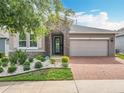 Charming home featuring a stone archway, brick driveway, and well-maintained landscaping at 224 Silver Maple Rd, Groveland, FL 34736