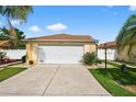 Well-maintained home featuring a two-car garage, manicured lawn, and neat landscaping at 2744 Gresham Ave, The Villages, FL 32162