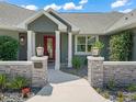 Charming front entrance with decorative stone pillars and a vibrant red door adding a pop of color at 563 Dowling Cir, Lady Lake, FL 32159