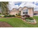 Well-kept house boasting a lush front lawn, charming landscaping, mature trees, and a two-car garage at 627 Leeds Pl, The Villages, FL 32162