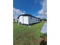 Exterior side view of home showing the lawn, air conditioning unit and a narrow sidewalk at 1005 Matthew Ave, Lady Lake, FL 32159