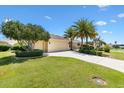 Beautiful exterior showcasing a well-maintained lawn, mature landscaping, and an attached two-car garage at 1123 Barnacle Ter, The Villages, FL 32162