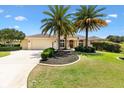 Charming one-story home featuring a well-manicured lawn, mature palm trees, and an attached two-car garage at 1123 Barnacle Ter, The Villages, FL 32162