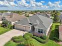 Overhead view of a well-maintained home featuring a three-car garage and landscaping in a residential neighborhood at 1304 Zombar Pl, The Villages, FL 32163