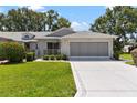Attached two-car garage with a paved driveway and tidy landscaping at 26030 Newcombe Cir, Leesburg, FL 34748