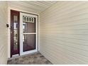 A close-up of the front entry, highlighting the storm door and patterned stone tiling at 26608 Racquet Cir, Leesburg, FL 34748