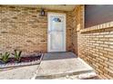 Close up of front door with white trim and brick accent with greenery at 3380 Blossom St, Kissimmee, FL 34746