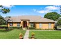 Charming exterior view of a single-story home with a red front door and well-manicured landscaping at 34021 Park Ln, Leesburg, FL 34788