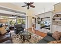 Open living room features hardwood floors, a built-in media center, and sliding glass doors to the sunroom at 34021 Park Ln, Leesburg, FL 34788